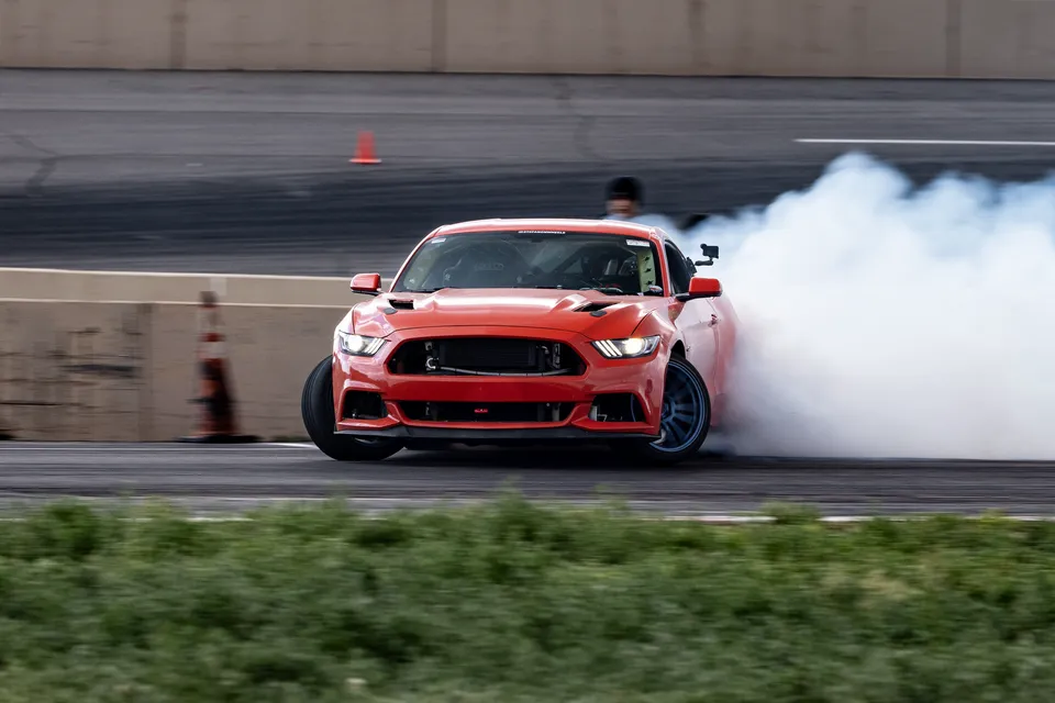 The Mustang coming head-on through tire smoke