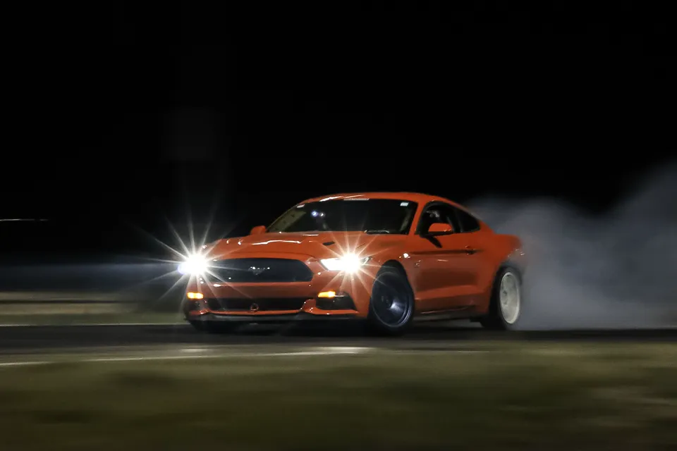 The Mustang drifting at night with its headlights on